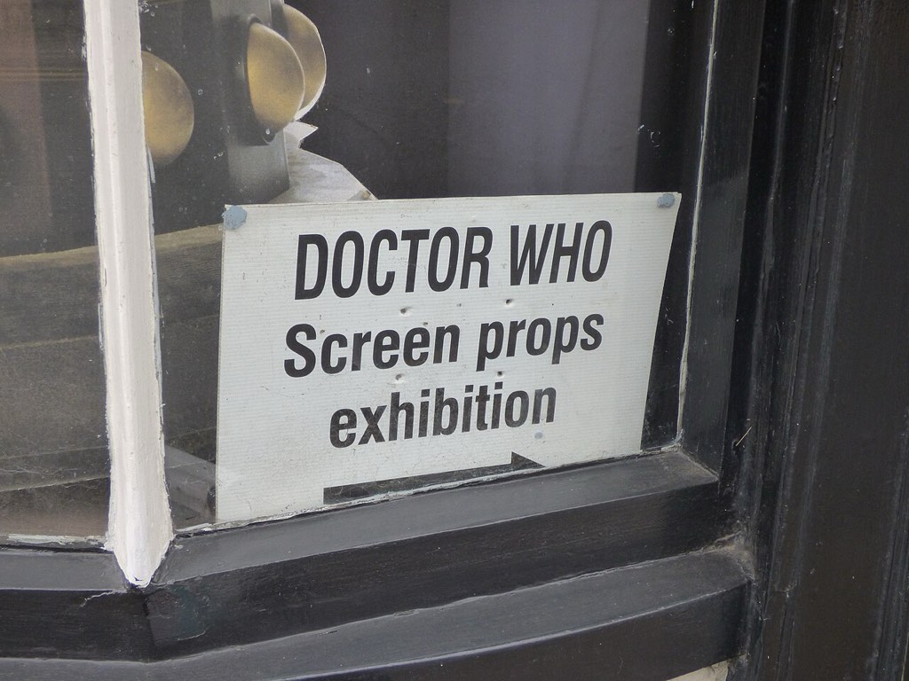 Rumen napis "Doctor Who Screen Props Exhibition" nad vrati v pritličju starinske zgradbe.
